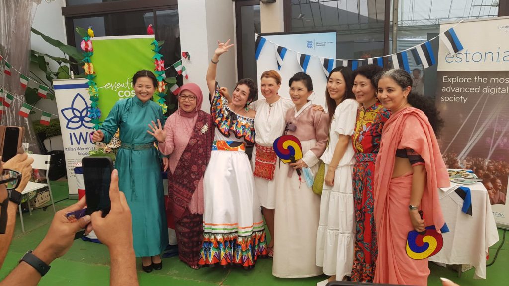 eight women with different traditional clothing standing and posing in front of a booth